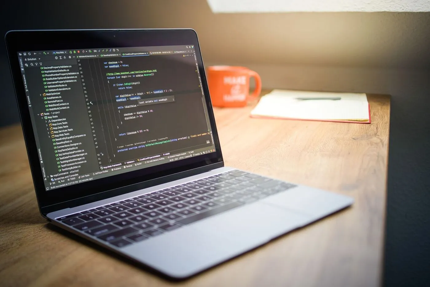 Portátil con código de programación en pantalla sobre una mesa de madera