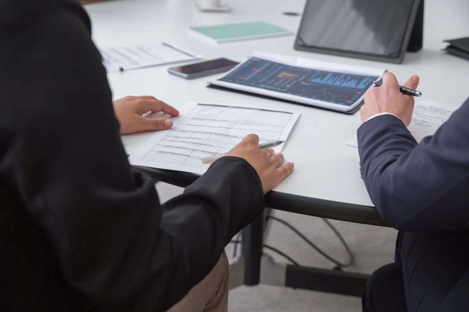 Dos personas revisando juntas datos e informes en una mesa de trabajo