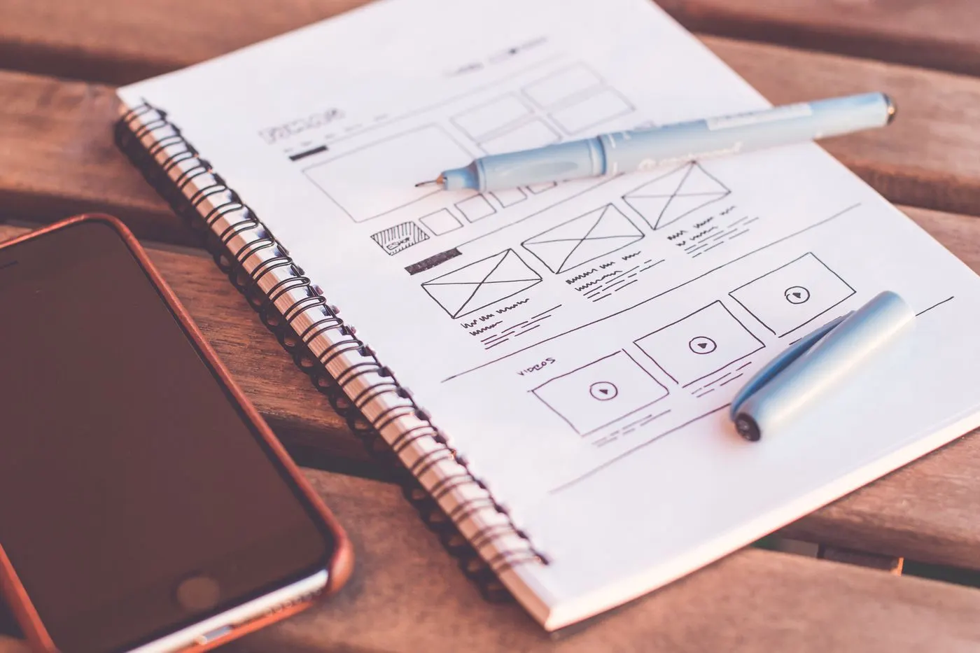 Boceto de wireframe de una web sobre un cuaderno, junto a un teléfono